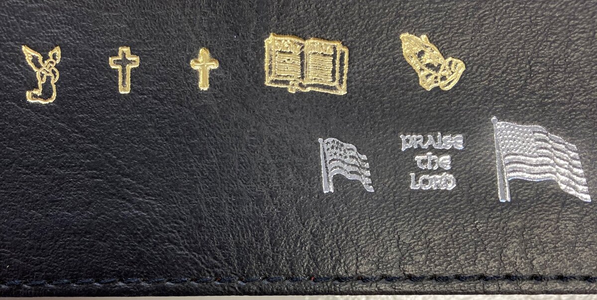 Gold and silver-colored imprint samples including crosses, an open Bible, praying hands and flags